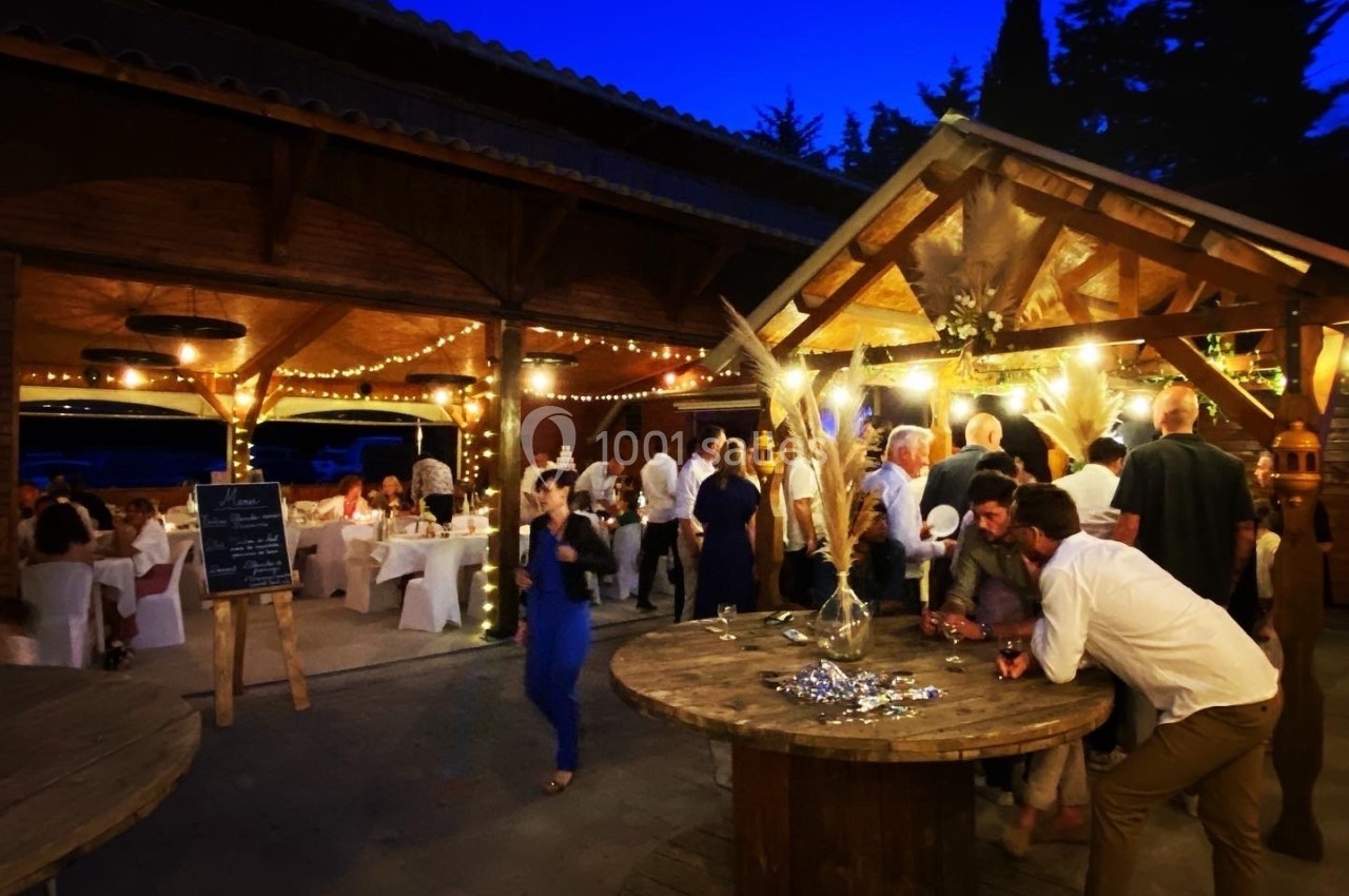 Groupe de personnes rassemblées en soirée dans un espace extérieur éclairé par des guirlandes lumineuses.
