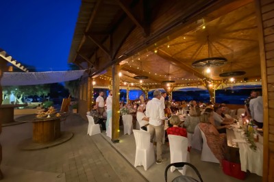 Massif de fleurs violettes au premier plan, terrasse en bois et ciel bleu en arrière-plan.