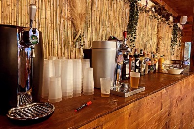 Massif de fleurs violettes au premier plan, terrasse en bois et ciel bleu en arrière-plan.