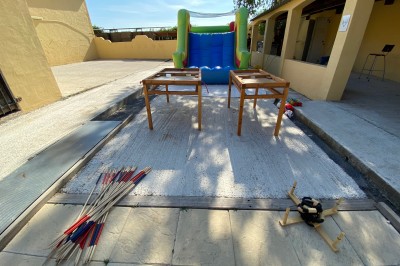 Massif de fleurs violettes au premier plan, terrasse en bois et ciel bleu en arrière-plan.