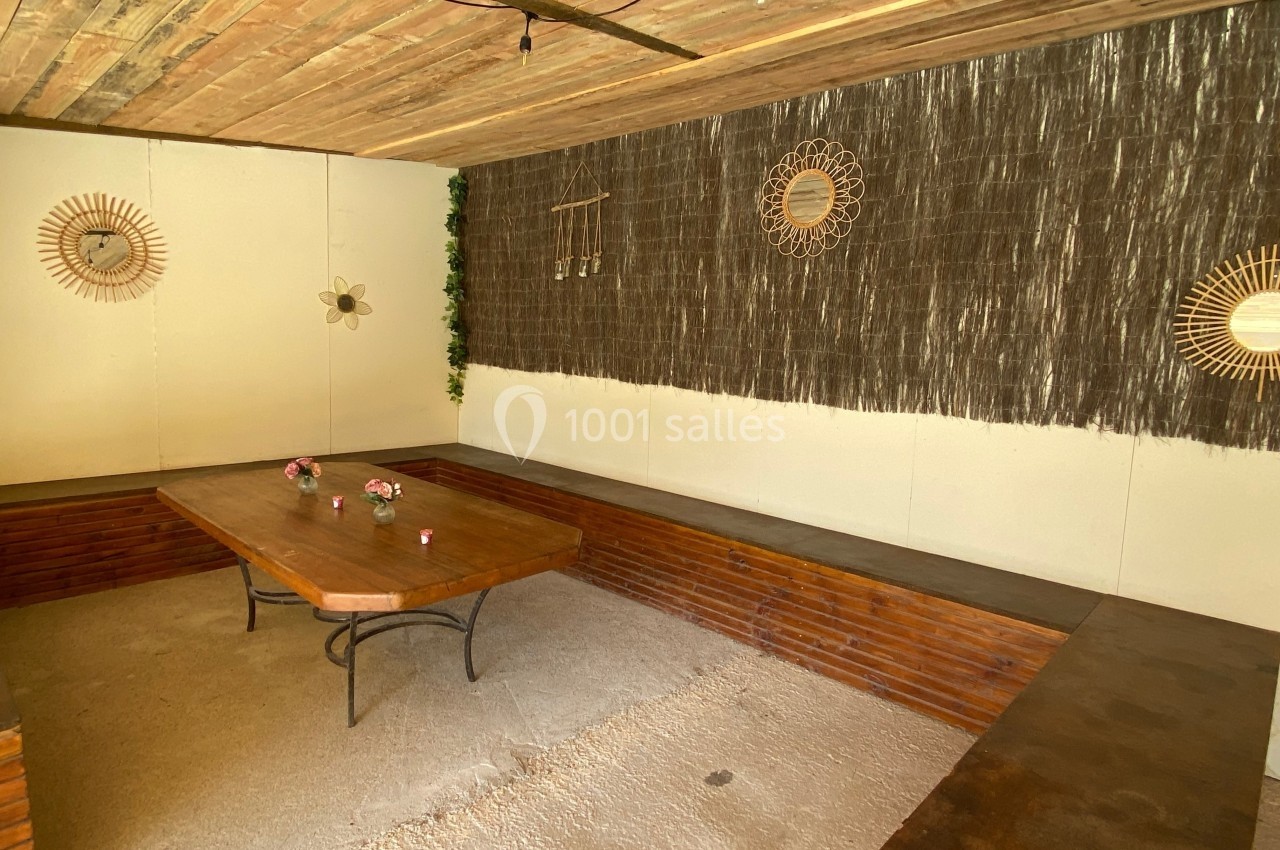 Salle avec table en bois, bancs intégrés, décoration murale en rotin et éclairage suspendu.