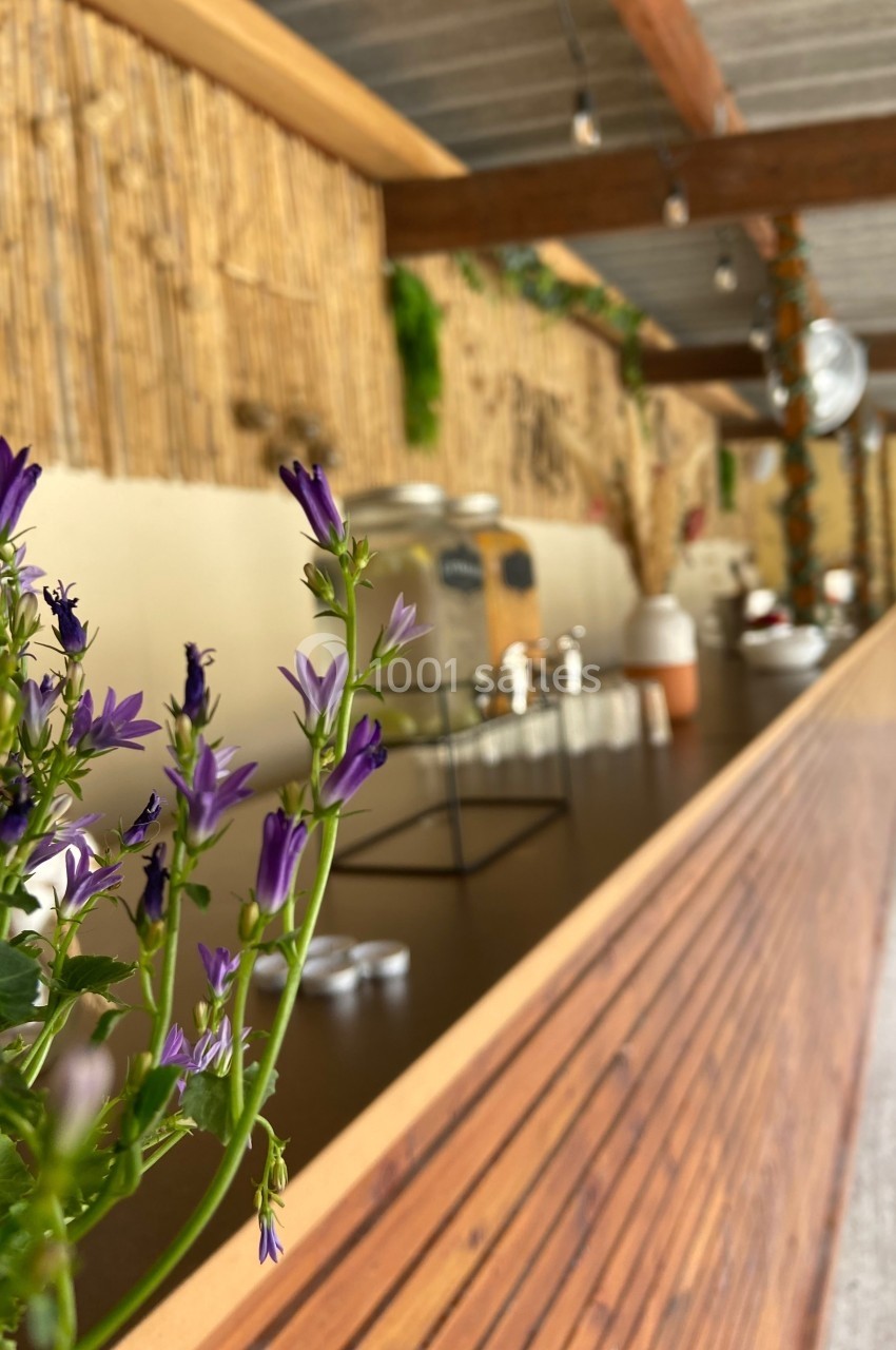 Fleurs violettes au premier plan avec un comptoir en bois et une décoration naturelle en arrière-plan.