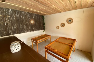 Massif de fleurs violettes au premier plan, terrasse en bois et ciel bleu en arrière-plan.