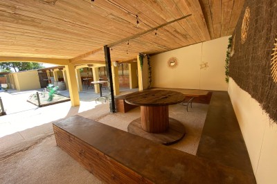 Massif de fleurs violettes au premier plan, terrasse en bois et ciel bleu en arrière-plan.