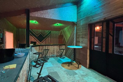 Massif de fleurs violettes au premier plan, terrasse en bois et ciel bleu en arrière-plan.