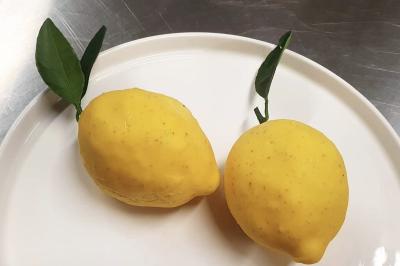 Cheesecake rond avec zeste de citron jaune et vert, sur une base de biscuit spéculoos.