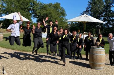 Miniature Traiteur Nousty (Pyrénées-Atlantiques) - Adquat Traiteur #5 Femme souriante cueillant des baies dans un jardin sous un parapluie par temps nuageux.