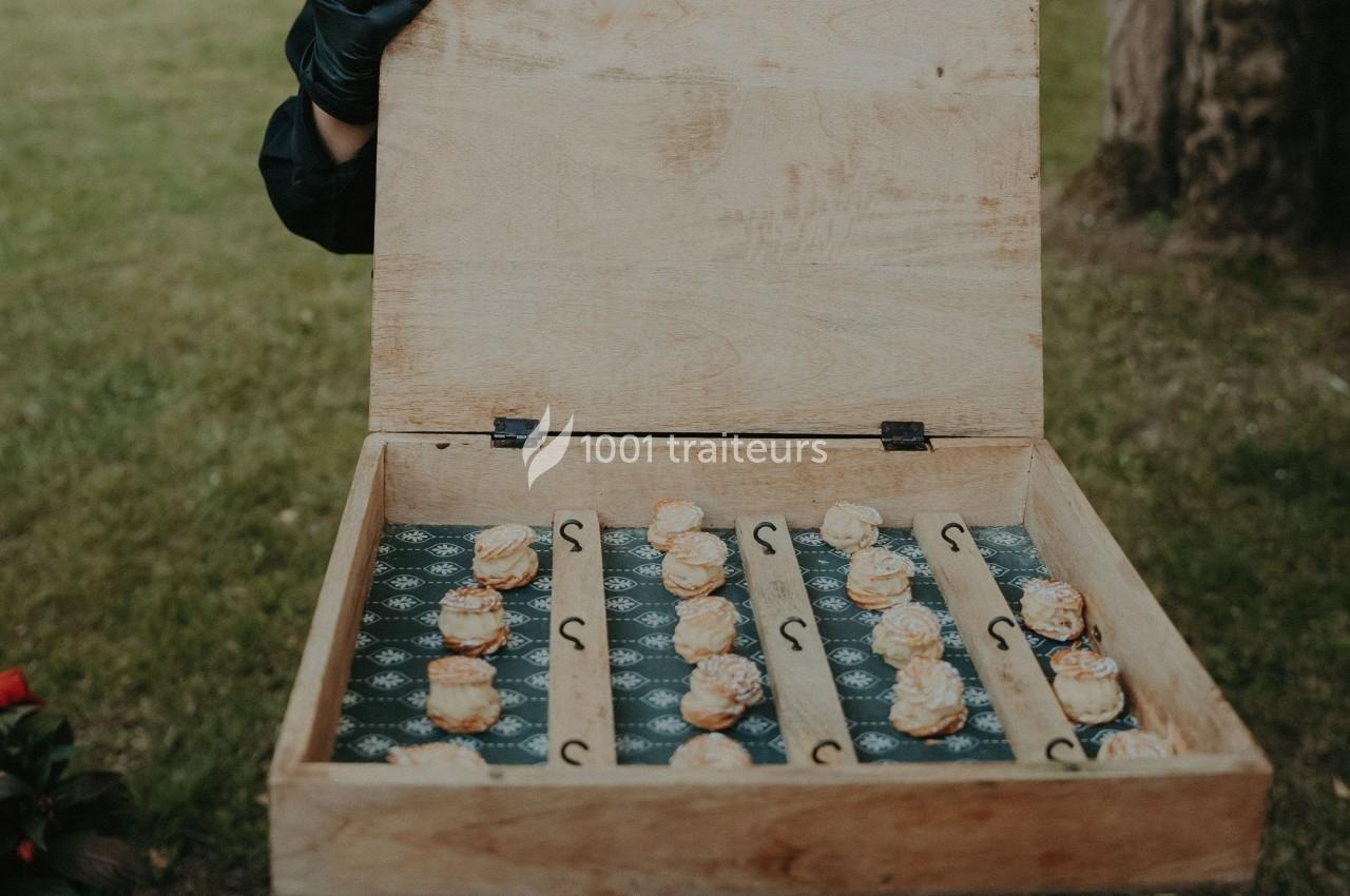 Boîte en bois ouverte contenant des pâtisseries individuelles disposées sur un fond à motifs.