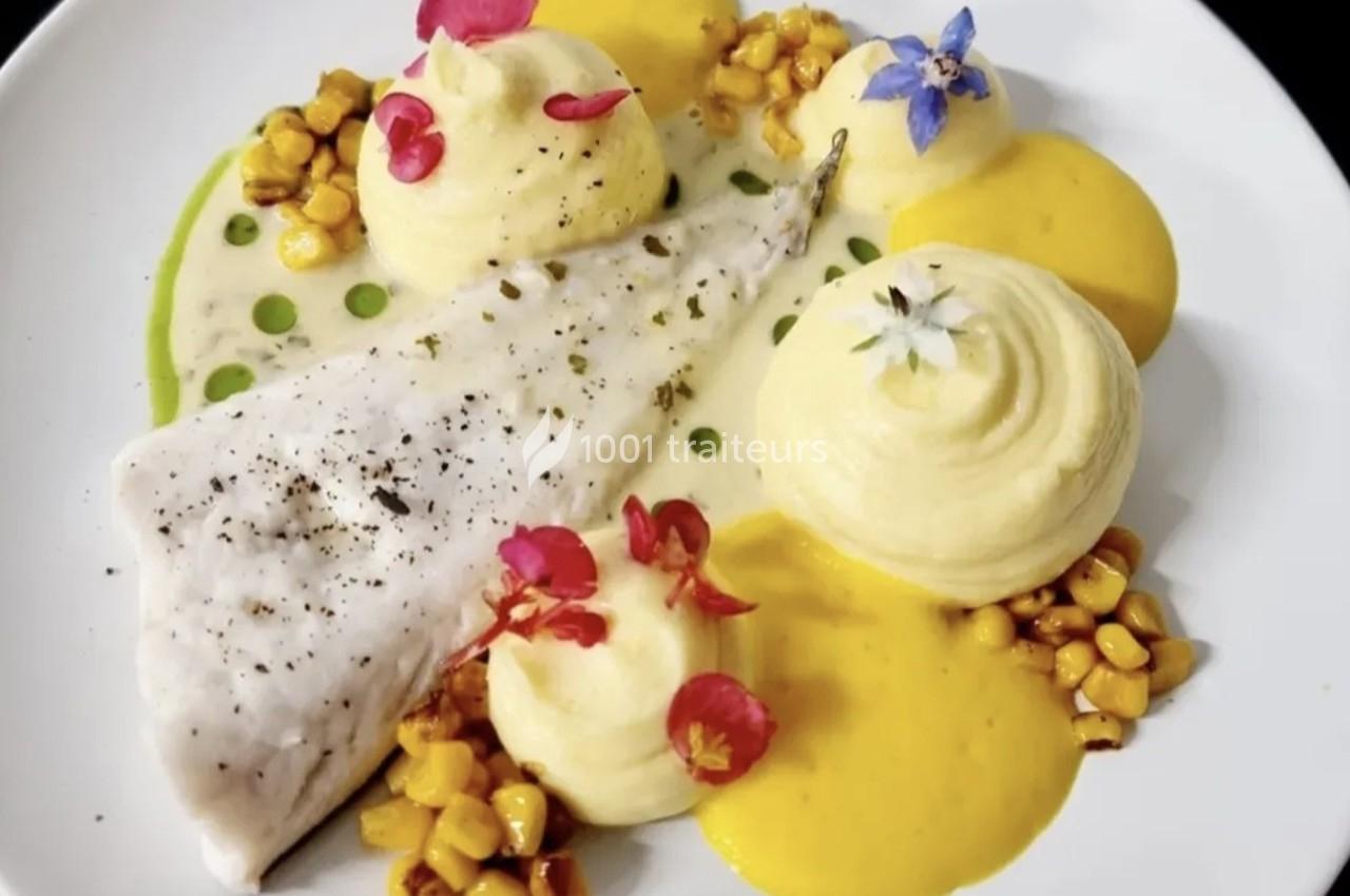 Filet de poisson blanc accompagné de purées, maïs grillé et fleurs comestibles sur une assiette blanche.