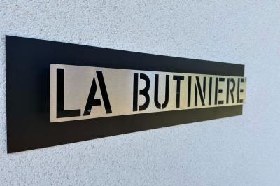 Des chèvres et des chevreaux devant une cabane en bois dans un enclos extérieur.