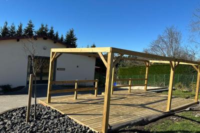 Des chèvres et des chevreaux devant une cabane en bois dans un enclos extérieur.