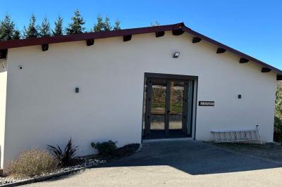Des chèvres et des chevreaux devant une cabane en bois dans un enclos extérieur.