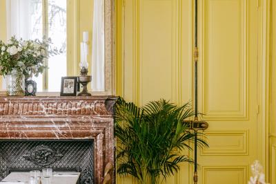 Façade d'une maison en briques avec toit mansardé, portail en fer forgé et arbres dénudés en premier plan.