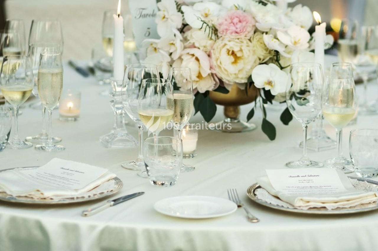 Table élégamment dressée avec des verres à pied, des assiettes, des menus et un centre de table floral.