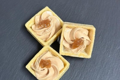 Plateau de bouchées apéritives garnies de mousse rose et décorées de feuilles de persil, disposées sur une grille.