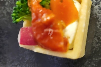 Plateau de bouchées apéritives garnies de mousse rose et décorées de feuilles de persil, disposées sur une grille.