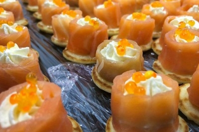 Plateau de bouchées apéritives garnies de mousse rose et décorées de feuilles de persil, disposées sur une grille.