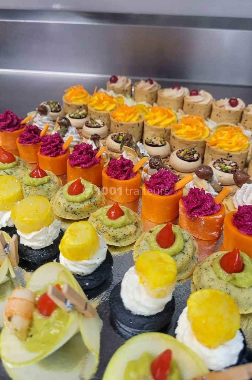 Assortiment de bouchées apéritives colorées disposées sur un plateau, comprenant légumes, fromages et garnitures variées.