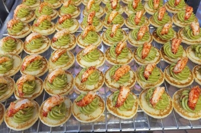 Plateau de bouchées apéritives garnies de mousse rose et décorées de feuilles de persil, disposées sur une grille.