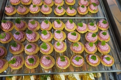 Plateau de bouchées apéritives garnies de mousse rose et décorées de feuilles de persil, disposées sur une grille.