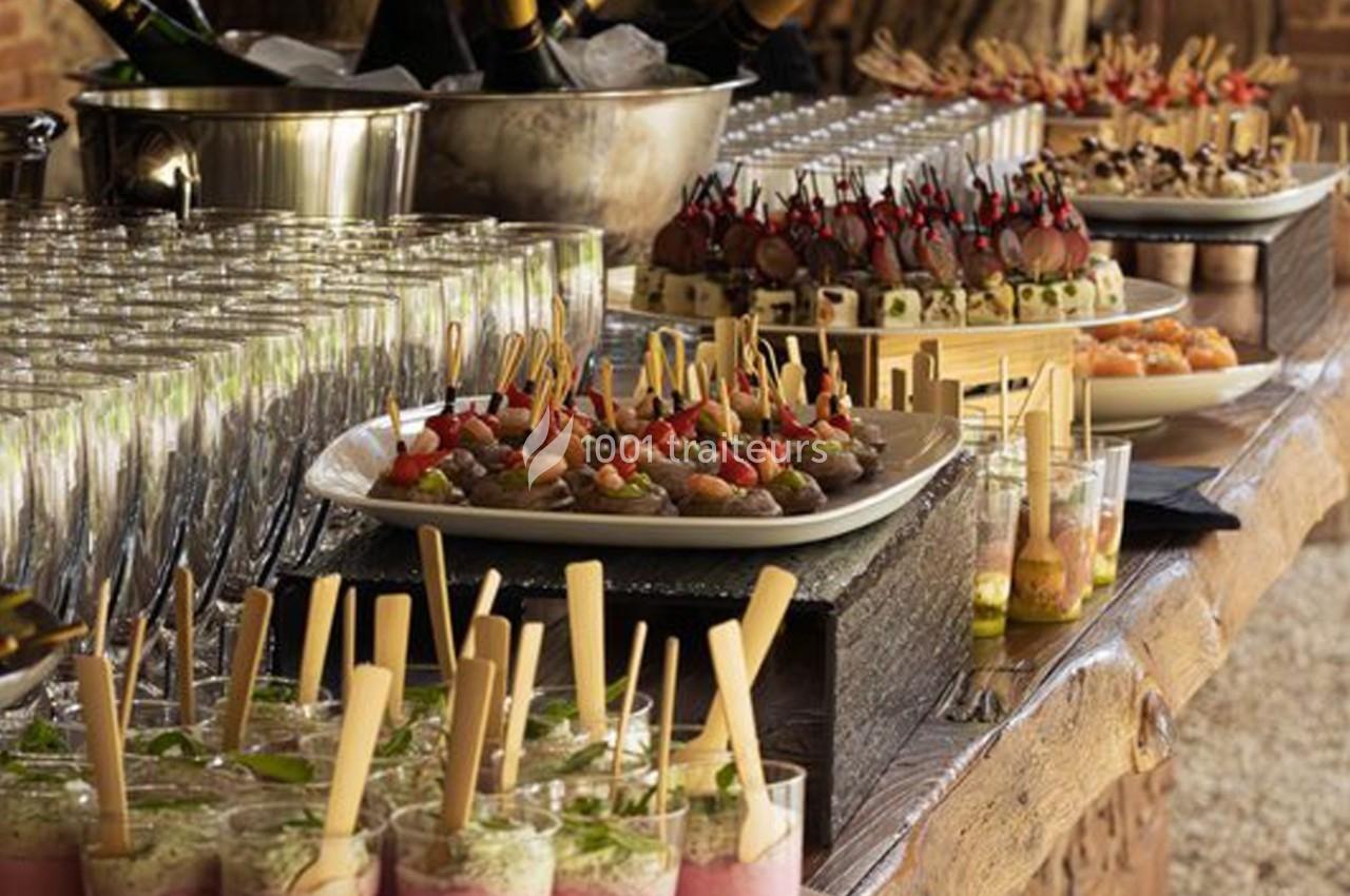 Buffet avec verrines, brochettes apéritives et desserts variés disposés sur une table en bois.