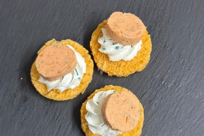 Plateau de bouchées apéritives garnies de mousse rose et décorées de feuilles de persil, disposées sur une grille.