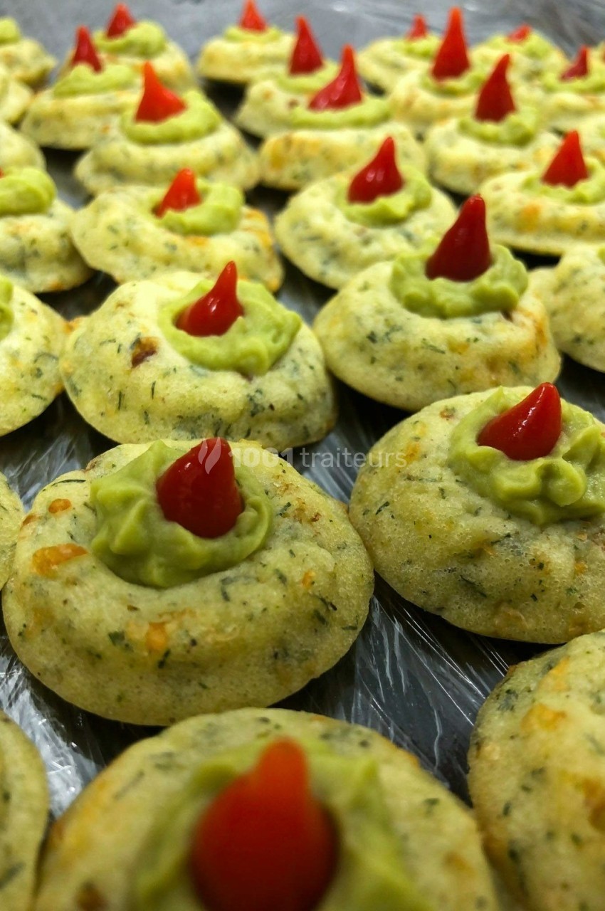 Biscuits salés garnis de crème verte et décorés d'un petit piment rouge au centre.