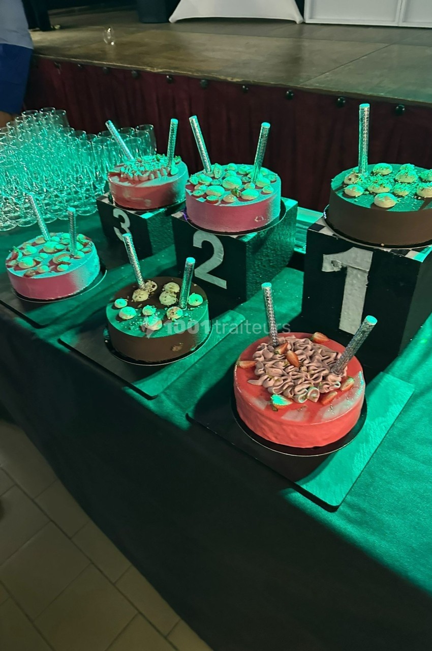 Des gâteaux décorés placés sur des podiums numérotés, entourés de verres en arrière-plan.