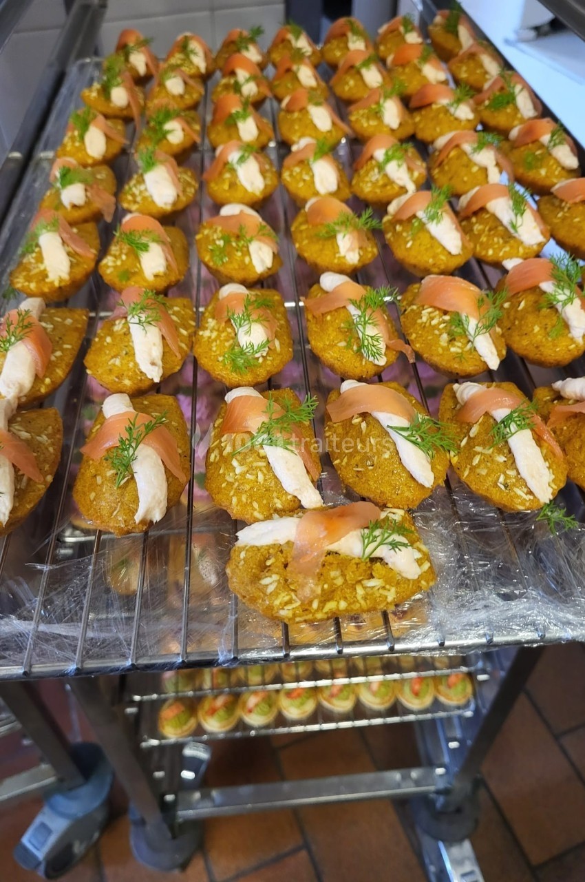 Plateau de bouchées apéritives à base de saumon fumé, crème et aneth, disposées sur une grille en cuisine.