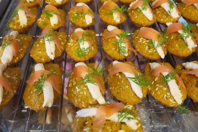 Plateau de bouchées apéritives garnies de mousse rose et décorées de feuilles de persil, disposées sur une grille.