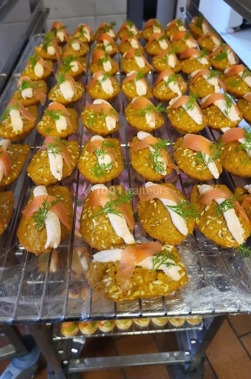 Bouchées de saumon fumé et fromage frais sur une base croustillante, garnies d'aneth, disposées sur des grilles.