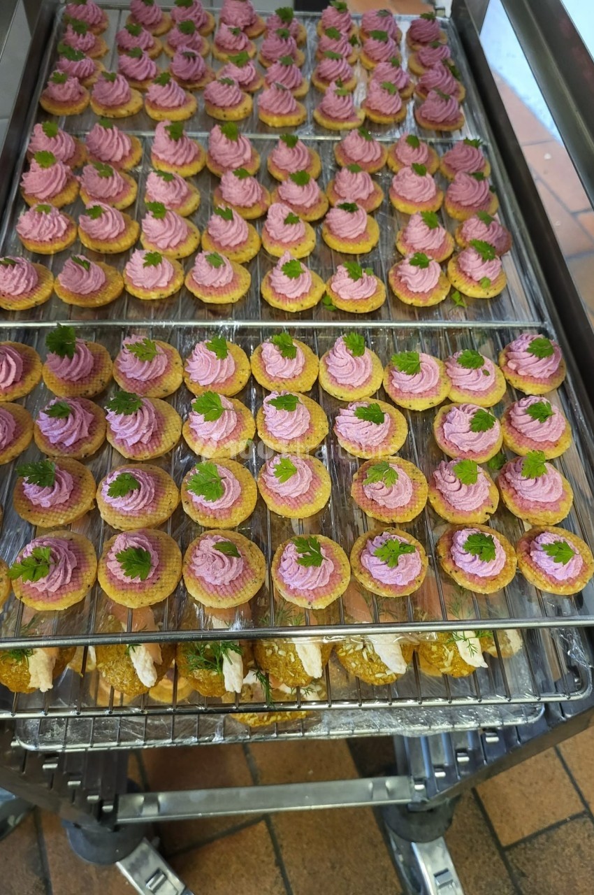 Plateau de bouchées apéritives garnies de mousse rose et décorées de feuilles de persil, disposées sur une grille.