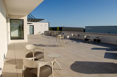 Salle spacieuse avec sol carrelé, éclairage moderne, grandes fenêtres et quelques tables hautes dispersées.