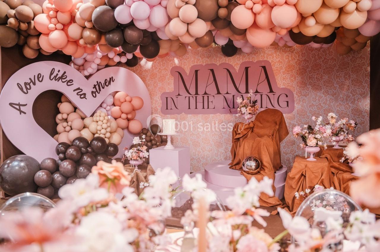 Décoration de fête avec ballons roses et bruns, fleurs, et inscriptions ’Mama in the making’ et ’A love like no other’.