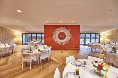 Bâtiment moderne avec façades vitrées et terrasses en bois, entouré de végétation au crépuscule.