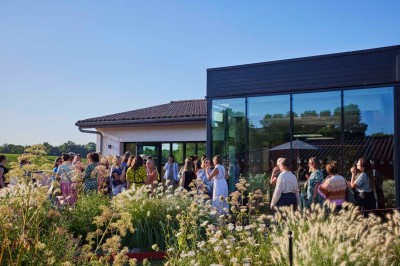 Bâtiment moderne avec façades vitrées et terrasses en bois, entouré de végétation au crépuscule.