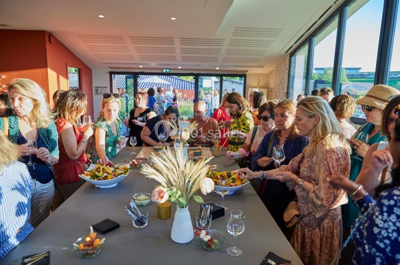 Groupe de personnes dégustant des plats et des boissons autour d'une table dans un espace lumineux avec vue extérieure.