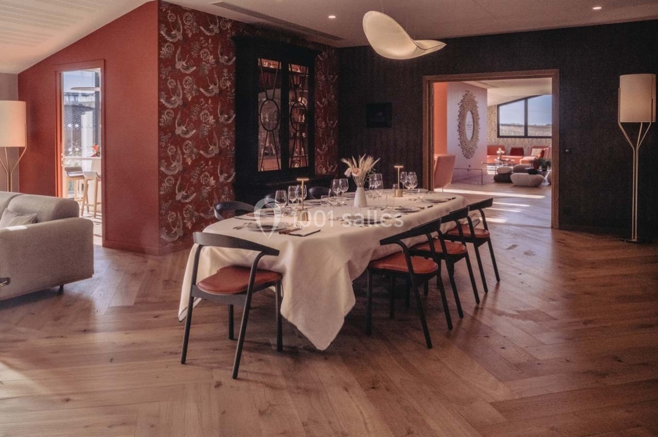 Salle à manger élégante avec une grande table dressée, éclairée par une lumière naturelle et entourée d'un décor chaleureux.