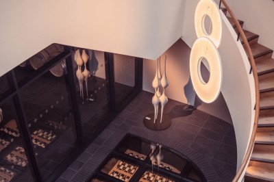 Bâtiment moderne avec façades vitrées et terrasses en bois, entouré de végétation au crépuscule.