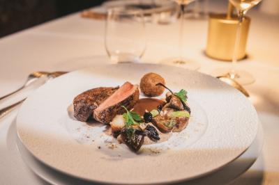 Bâtiment moderne avec façades vitrées et terrasses en bois, entouré de végétation au crépuscule.