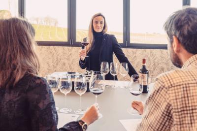 Bâtiment moderne avec façades vitrées et terrasses en bois, entouré de végétation au crépuscule.