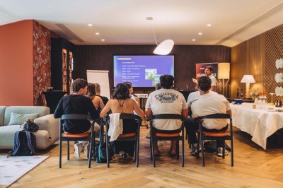 Vue aérienne d'une terrasse animée entourée de vignes au coucher du soleil, avec des invités profitant du cadre.