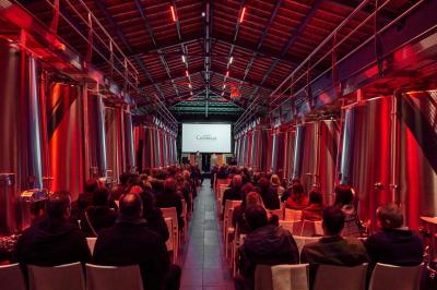 Vue aérienne d'une terrasse animée entourée de vignes au coucher du soleil, avec des invités profitant du cadre.