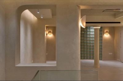 Deux lavabos en pierre avec un vase de fleurs roses et jaunes, placés devant un miroir ondulé.