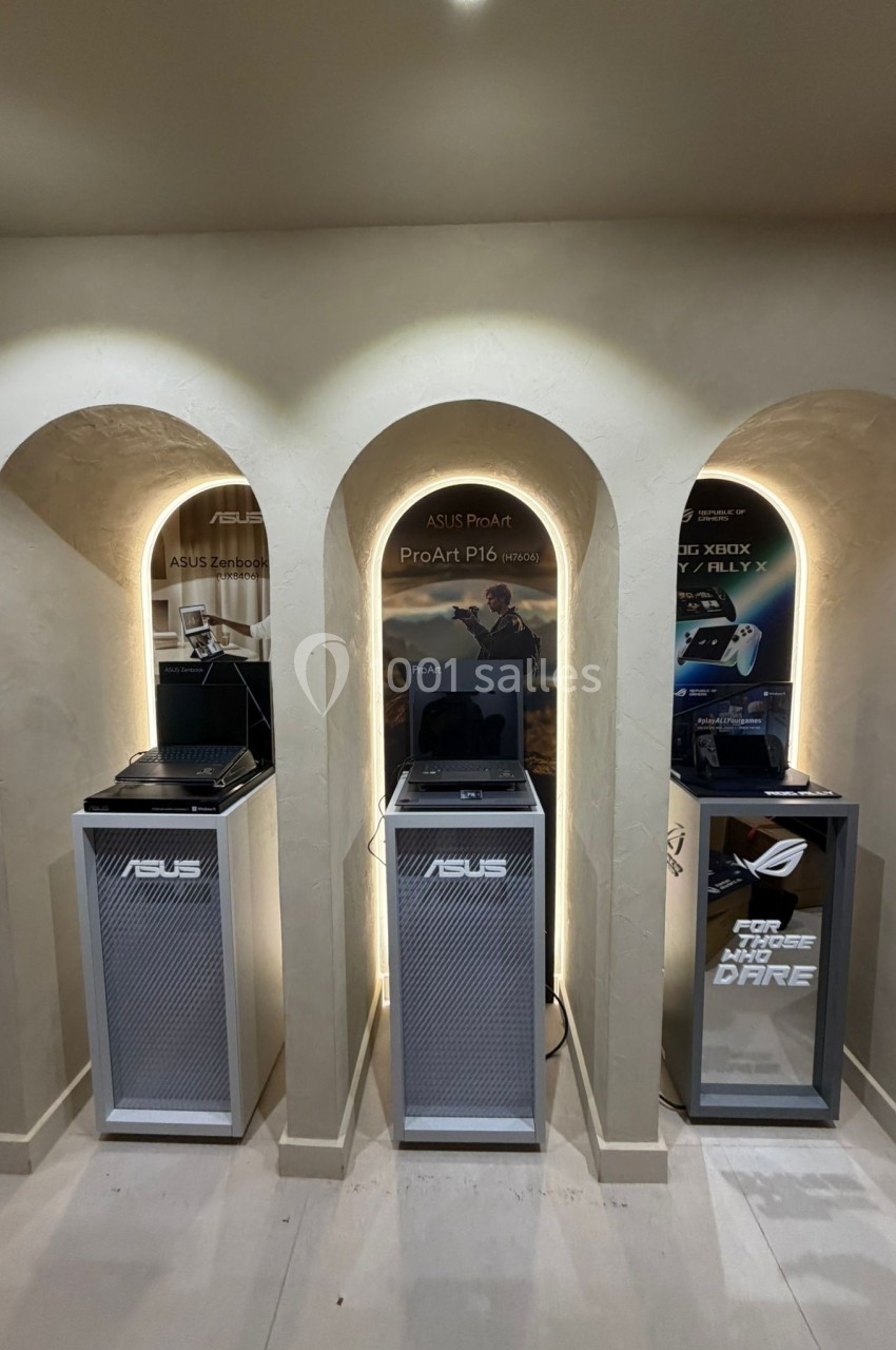 Trois ordinateurs portables exposés dans des niches éclairées, accompagnés de panneaux promotionnels ASUS.