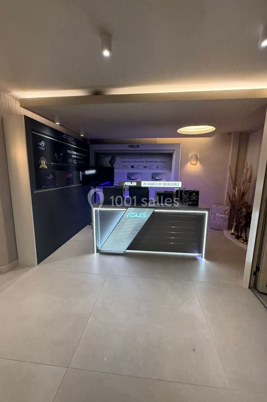 Comptoir d'accueil moderne avec éclairage LED, écrans et présentoirs dans un espace intérieur épuré.