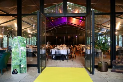 Miniature Location salle Gouvieux (Oise) - La Serre de Jeanne #3 Salle de réception vitrée avec tables décorées, entourée de verdure visible à travers les baies.