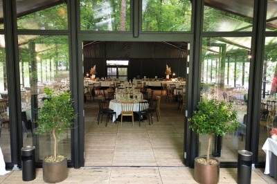 Miniature Location salle Gouvieux (Oise) - La Serre de Jeanne #14 Salle de réception vitrée avec tables décorées, entourée de verdure visible à travers les baies.