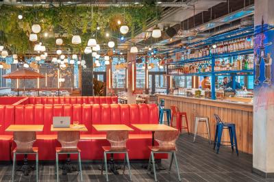 Façade d'un bâtiment moderne avec de grandes fenêtres, des arbres devant et une entrée vitrée portant le nom ’Eklo’.