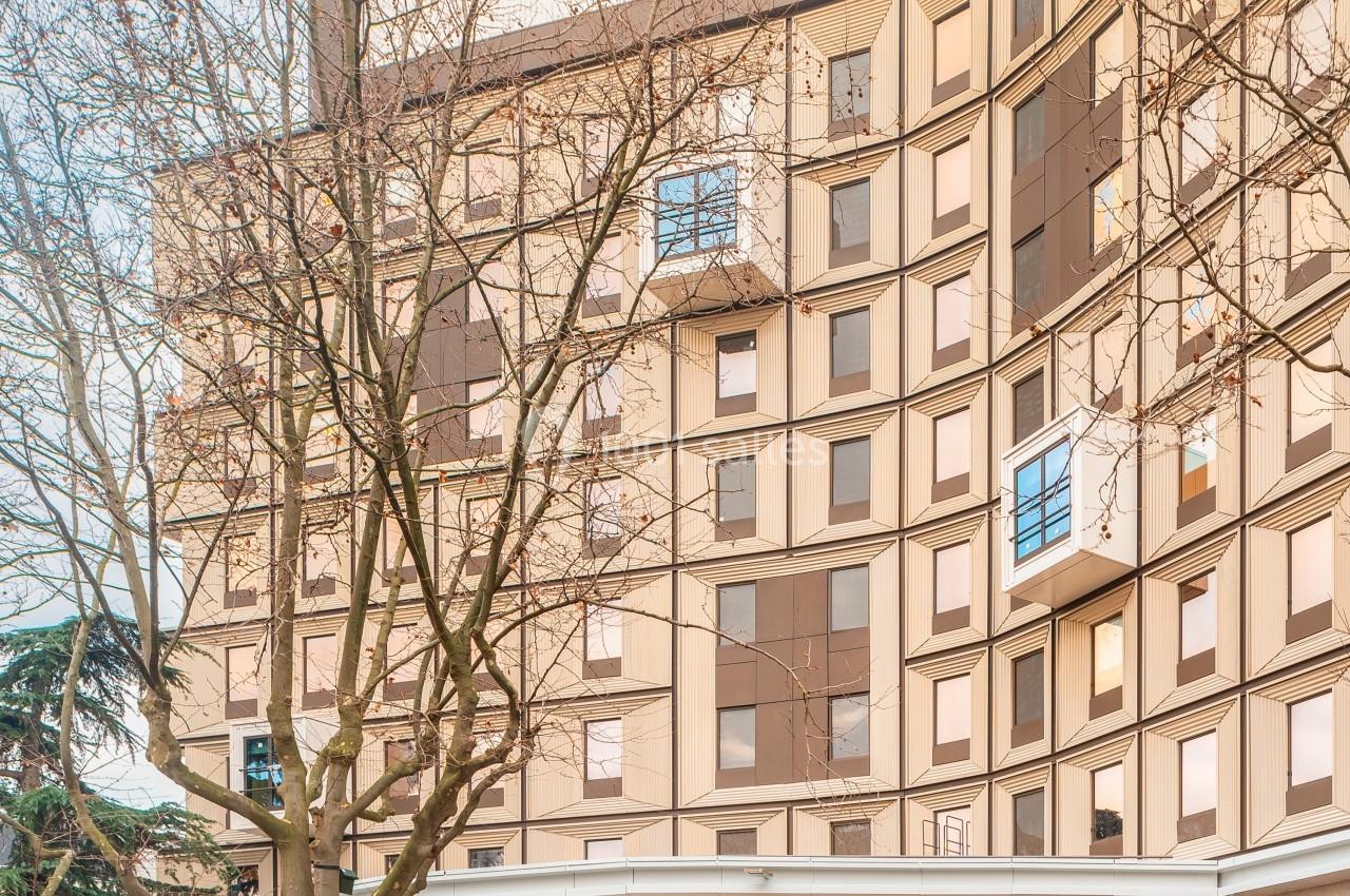 Façade d'un bâtiment moderne avec de grandes fenêtres, des arbres devant et une entrée vitrée portant le nom ’Eklo’.